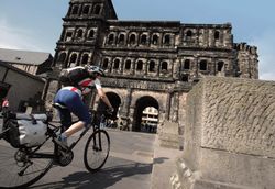Trier, Kultur im Gepäck Porta Nigra in Trier © Mosellandtouristik GmbH Radfahrer fährt in der Nähe der Porta Nigra, die im Hintergrund zu sehen ist, entlang.