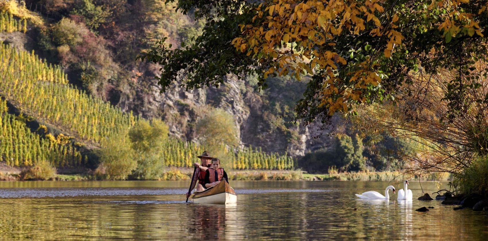 Idyllische Mosel-Kanufahrt © Christopher Arnoldi Zwei Personen im Kanu auf dem Fluss, daneben zwei Schwäne