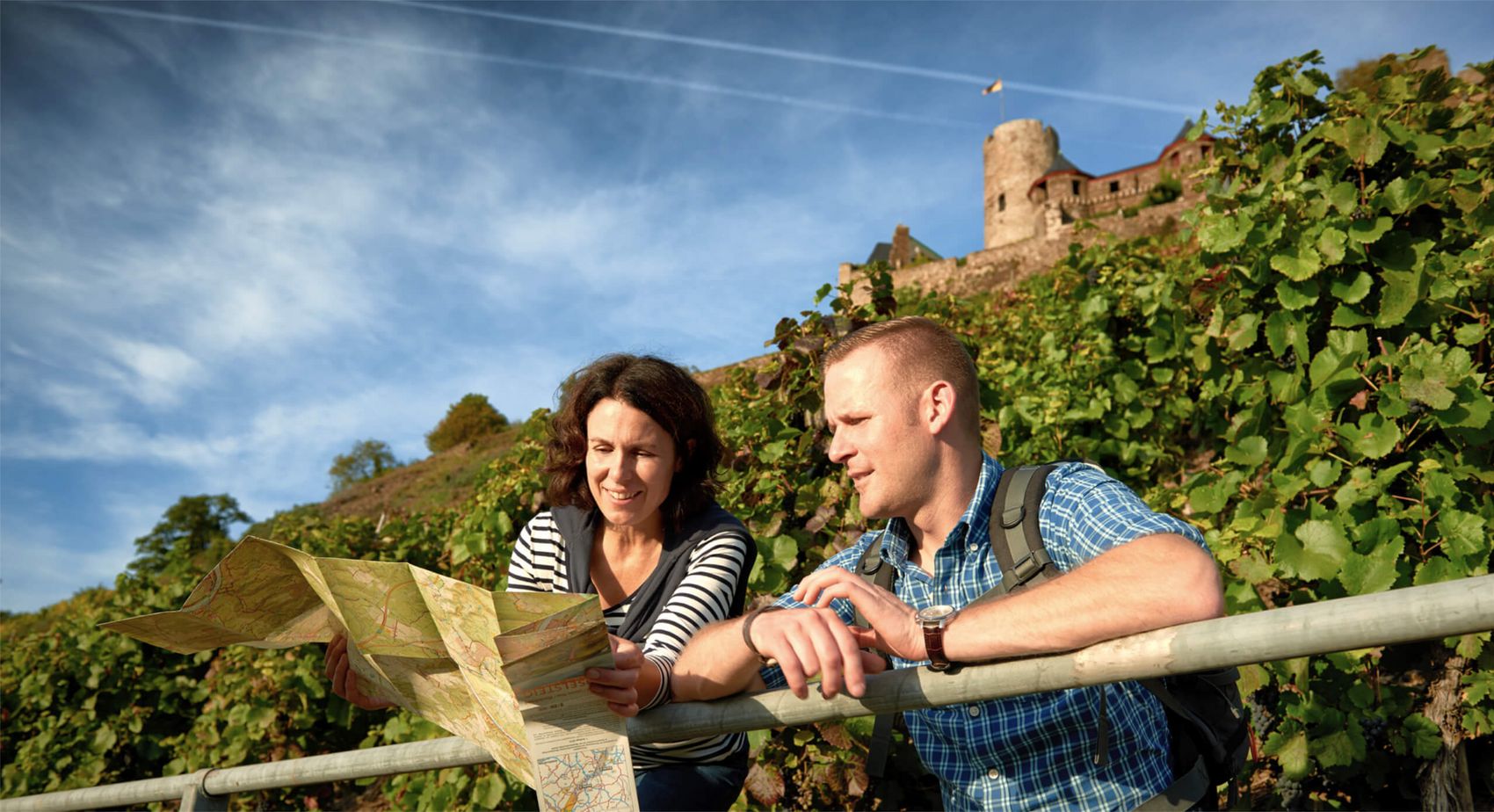 Alken, Burg Thurant wandernd entdecken © Mosellandtouristik GmbH / Christopher Arnoldi Wanderer mit Wanderkarte vor Weinbergskulisse und Burg