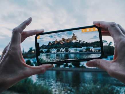 Saarburg, Ansicht der Burganlage mit der ARGO App © Travelisto Hände halten Smartphone, Bildschirm zeigt Burganlage auf Berg