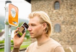 Mann mit Handy am Ohr an der Lauschtour Station Römische Villa Longuich