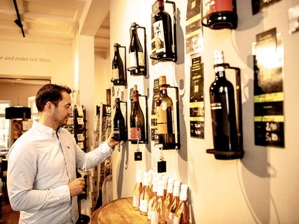 Trier, Vinothek © Mosellandtouristik GmbH/Dominik Ketz Ansicht auf einen Mann, der in einer Vinothek einen Wein aussucht.