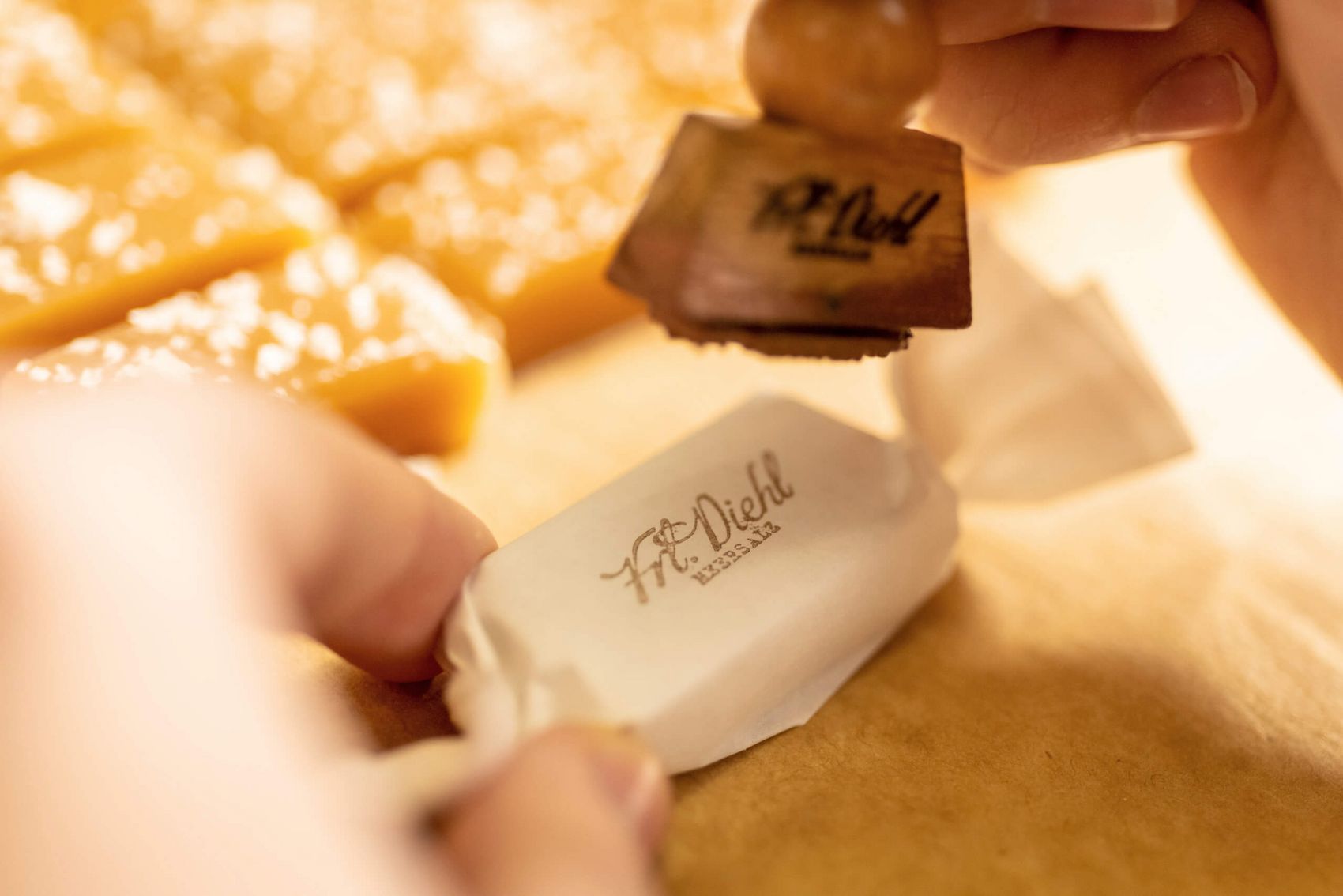 Koblenz, Produktveredelung in der Karamellmanufaktur Fräulein Diehl © Mosellandtouristik GmbH / Dominik Ketz Karamellbonbon mit weißem Papier verpackt wird gestempelt