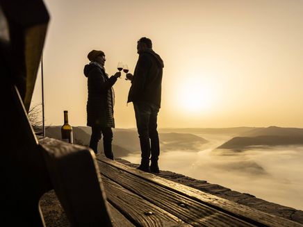 Weingenuss im Winter © Mosellandtouristik GmbH / Dominik Ketz Paar im Winter auf dem Berg stößt mit Wein an, Sonne und Nebel im Tal