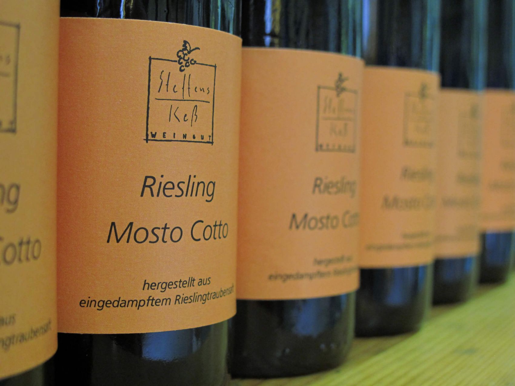 Reil, Weinessig vom Weingut Steffens-Keß © Harald Steffens Essig in Weinflaschen mit orangenem Etikett aufgereiht nebeneinander
